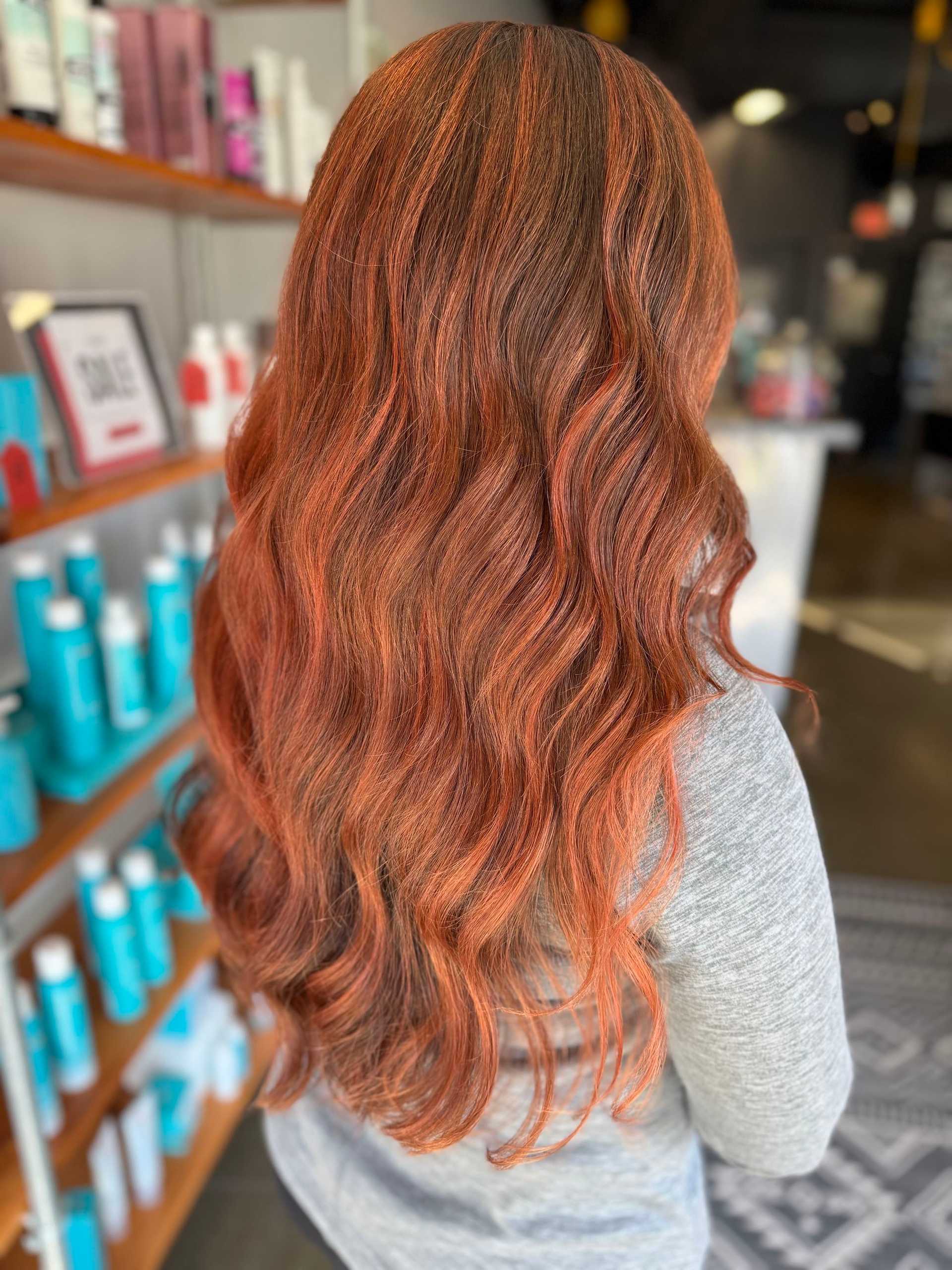 Long wavy red-brown hair styled in a salon setting.