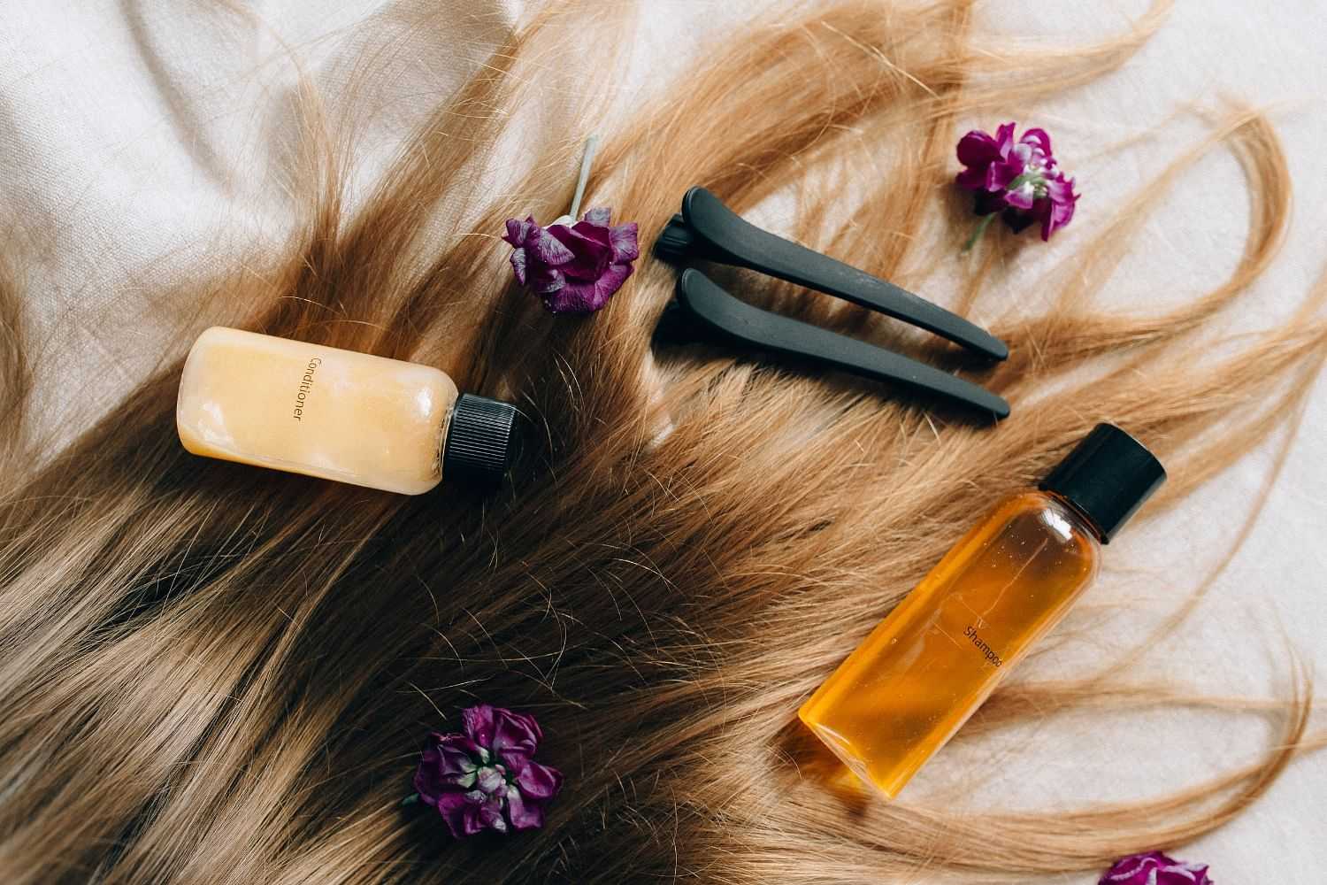 Hair care products and flowers on flowing brown hair.